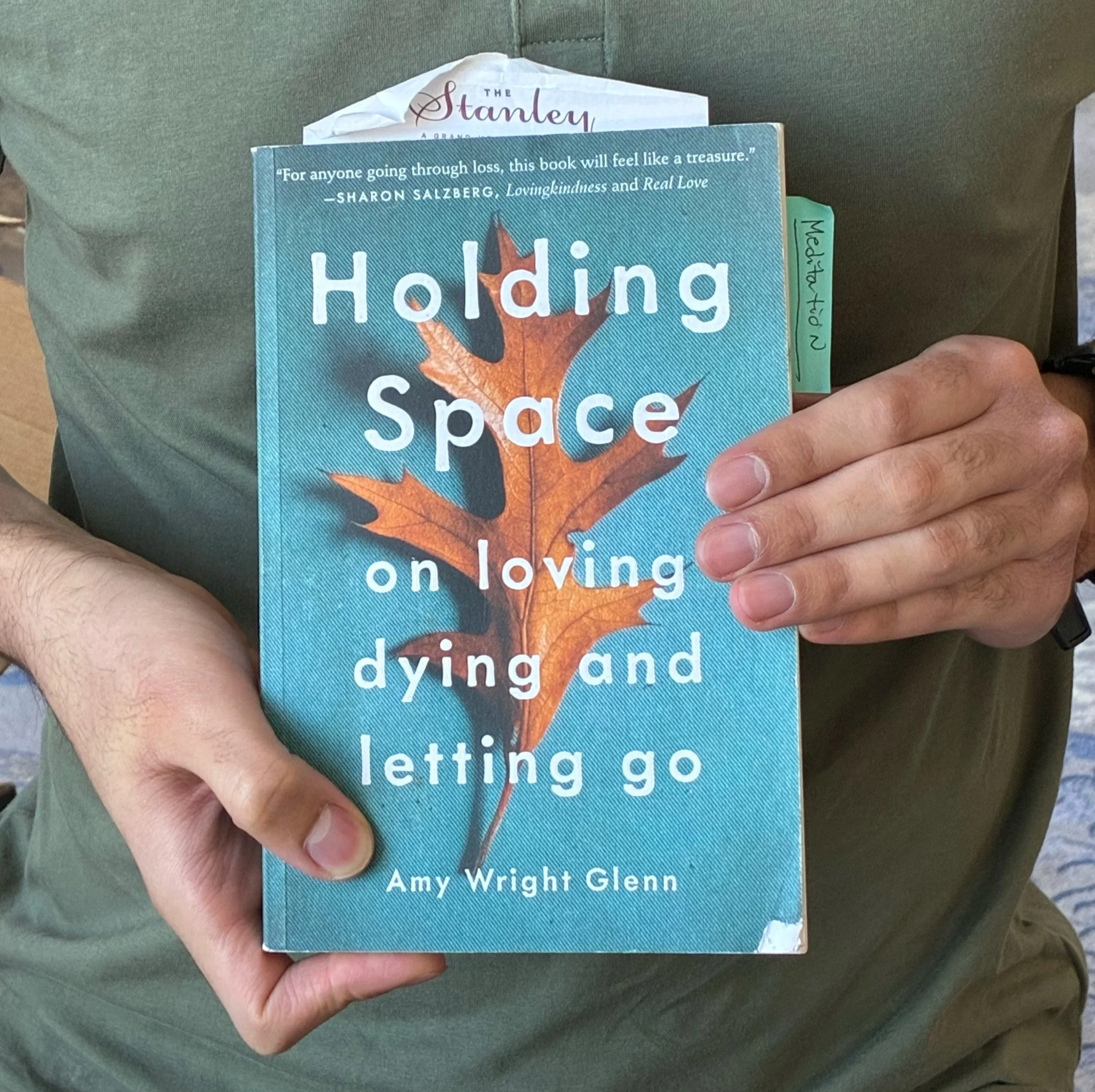 Man in a green shirt holding the book " Holding Space" by Amy Wright Glenn