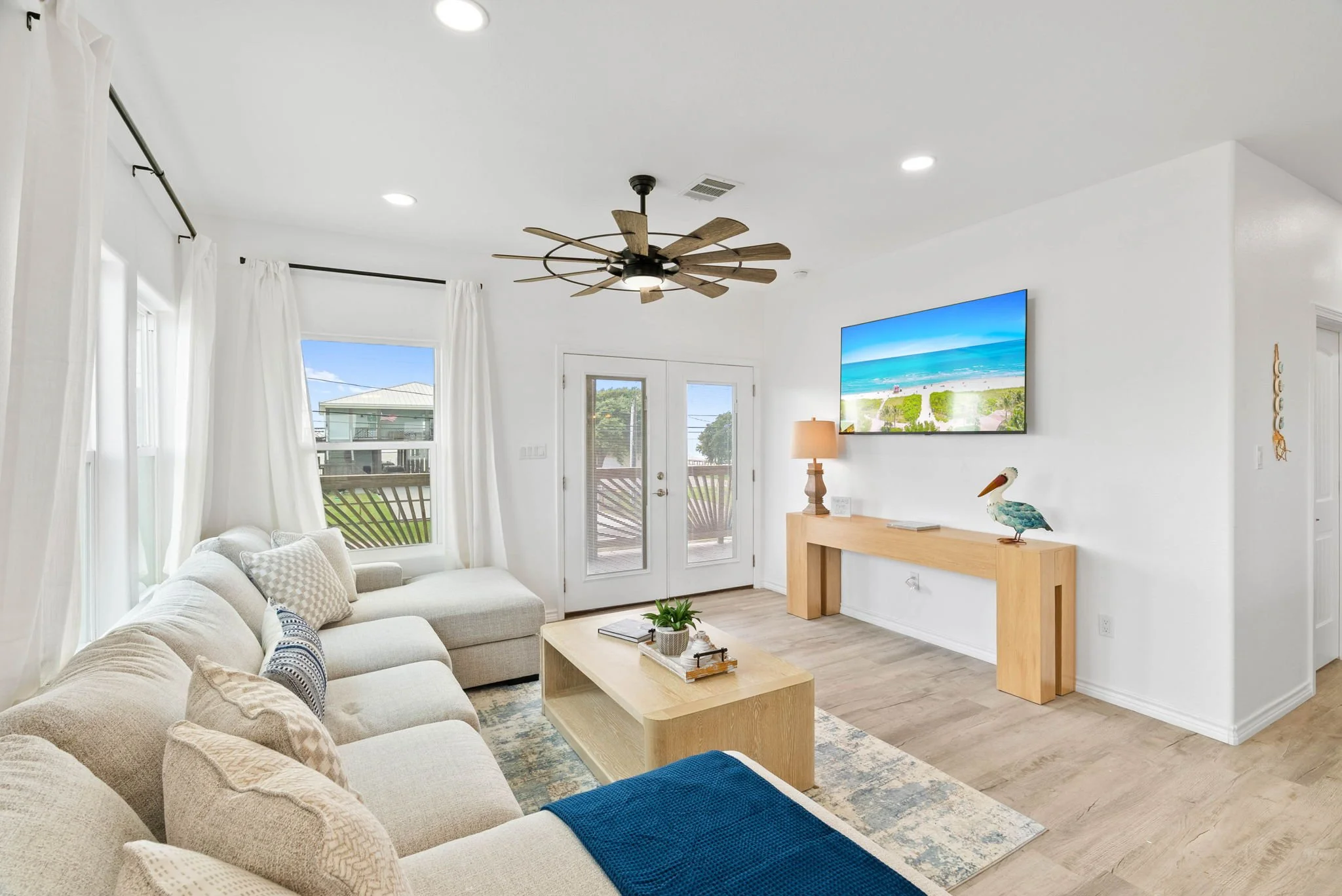 Bright living room with sectional sofa, wall-mounted TV and balcony doors