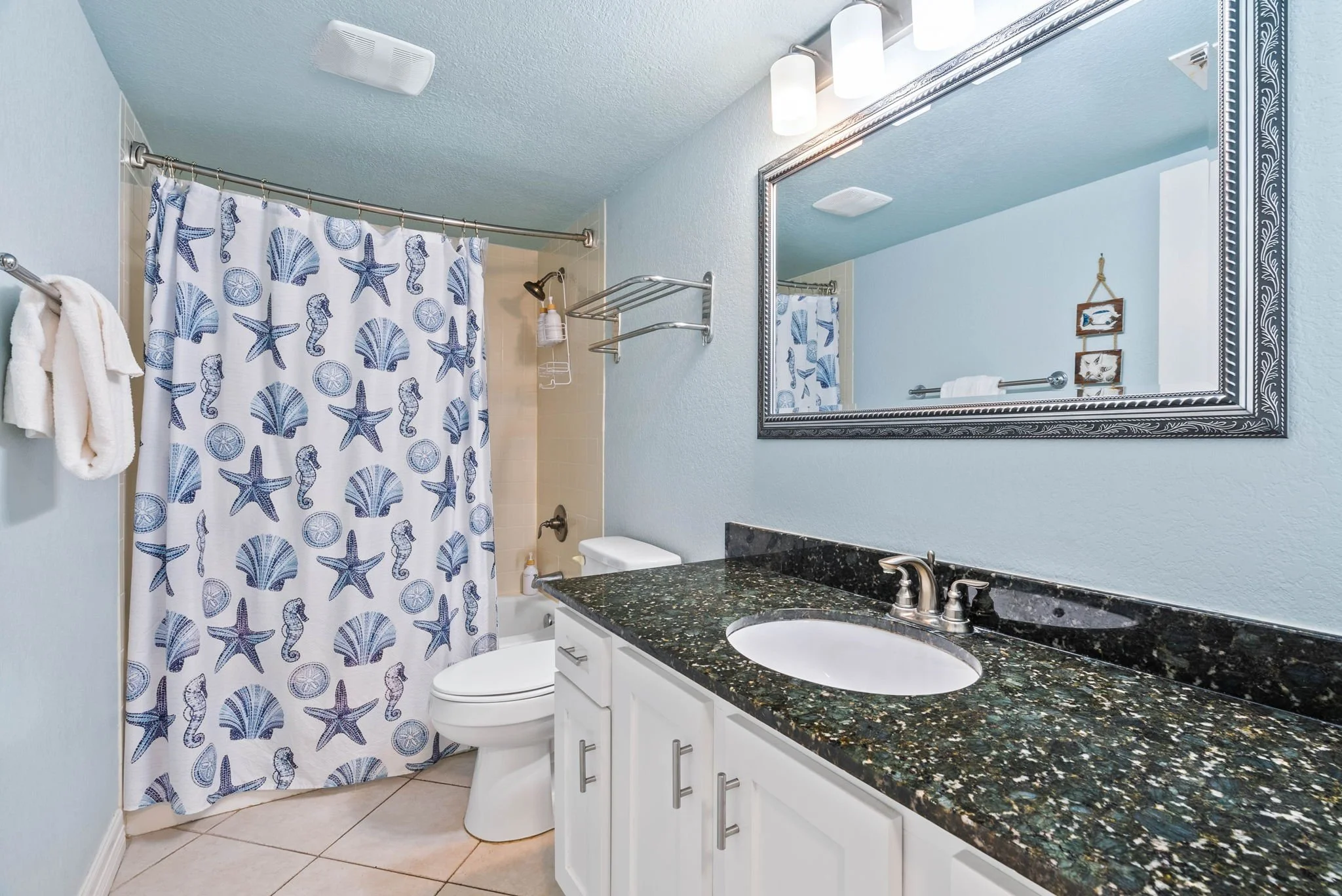 Coastal bathroom with granite vanity and seashell shower curtain at Tradewinds condo, Laguna Reef Rockport TX