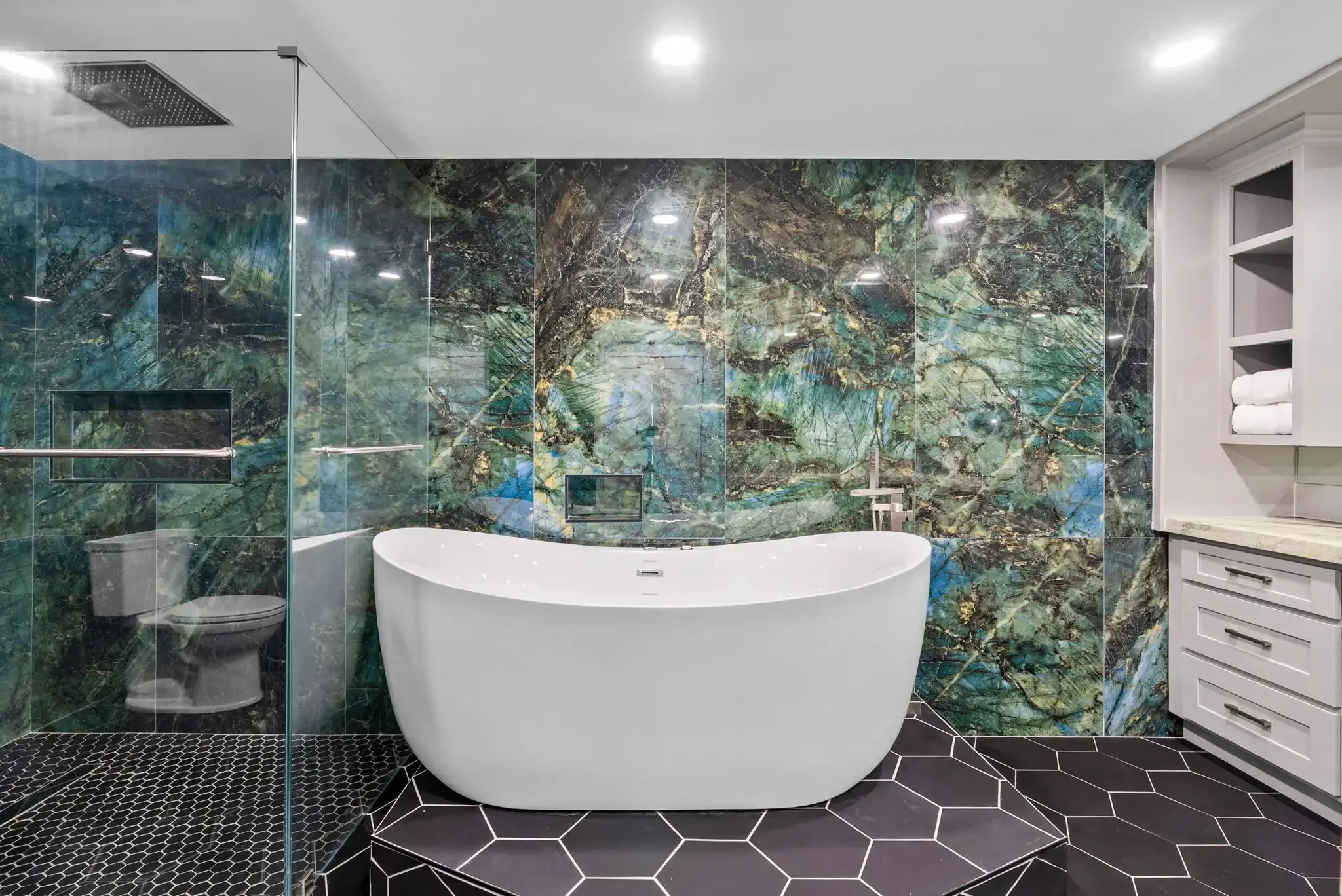 Luxury primary bathroom with freestanding soaking tub and dramatic stone accent wall in a Rockport TX vacation rental.