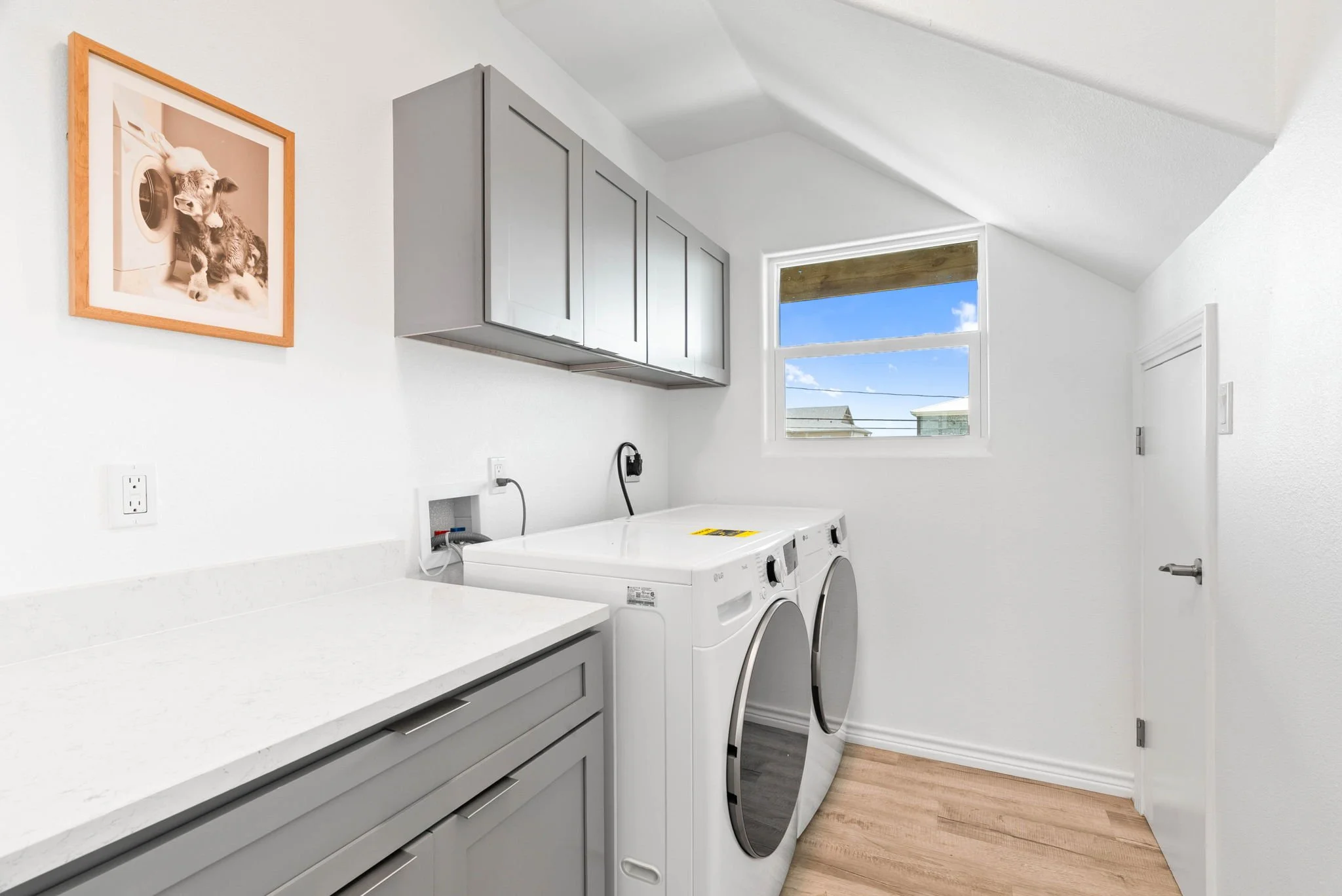 Full laundry room with washer, dryer, quartz counter and storage cabinets