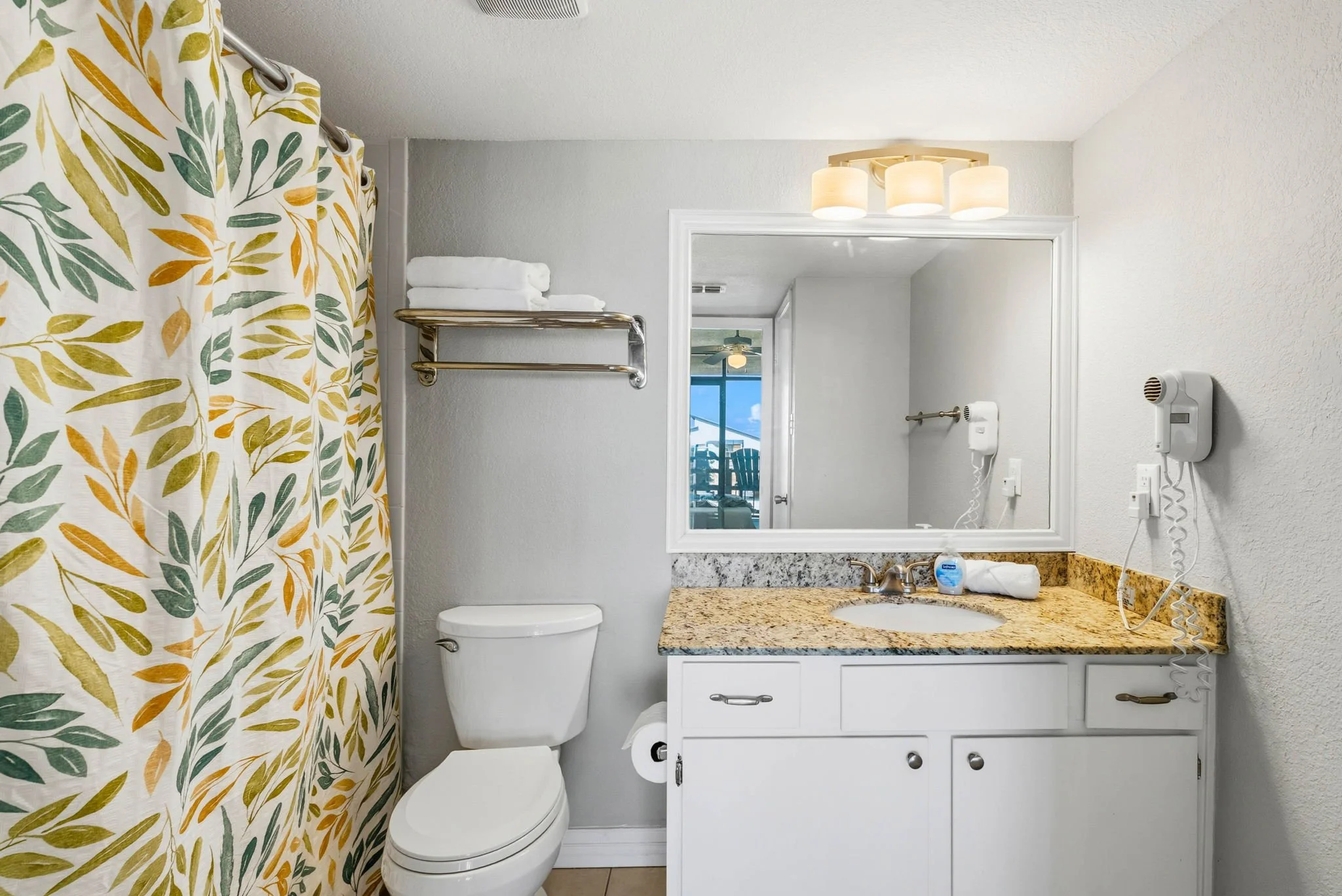 Bright coastal-style bathroom with granite countertop in Peaceful Pelican Laguna Reef condo