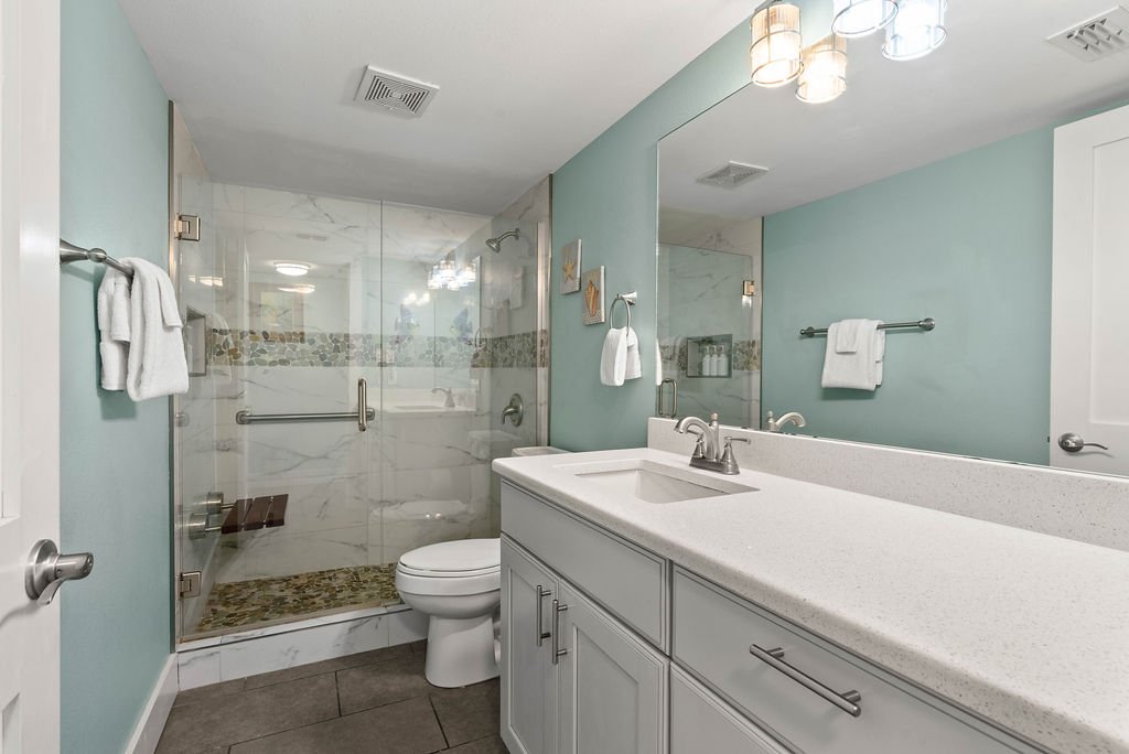 Elegant bathroom with walk-in glass shower and coastal blue walls at Beauty Blues vacation rental, Rockport TX.
