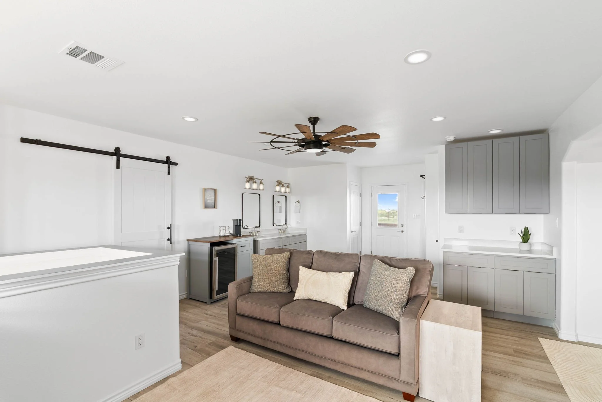 Spacious upper-level lounge with sofa, double vanity and gray built-in cabinetry