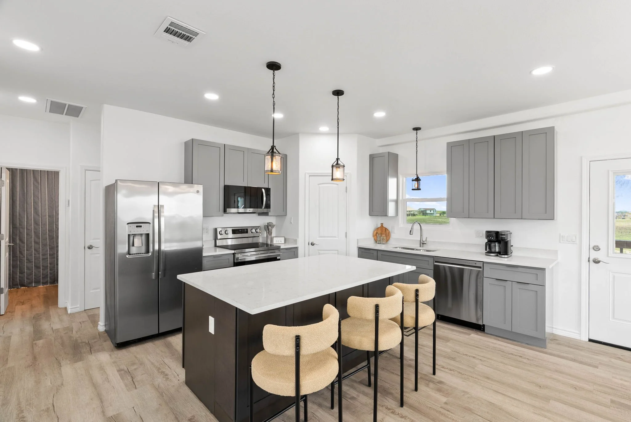Modern kitchen with quartz island, gray cabinets, stainless appliances and bar seating