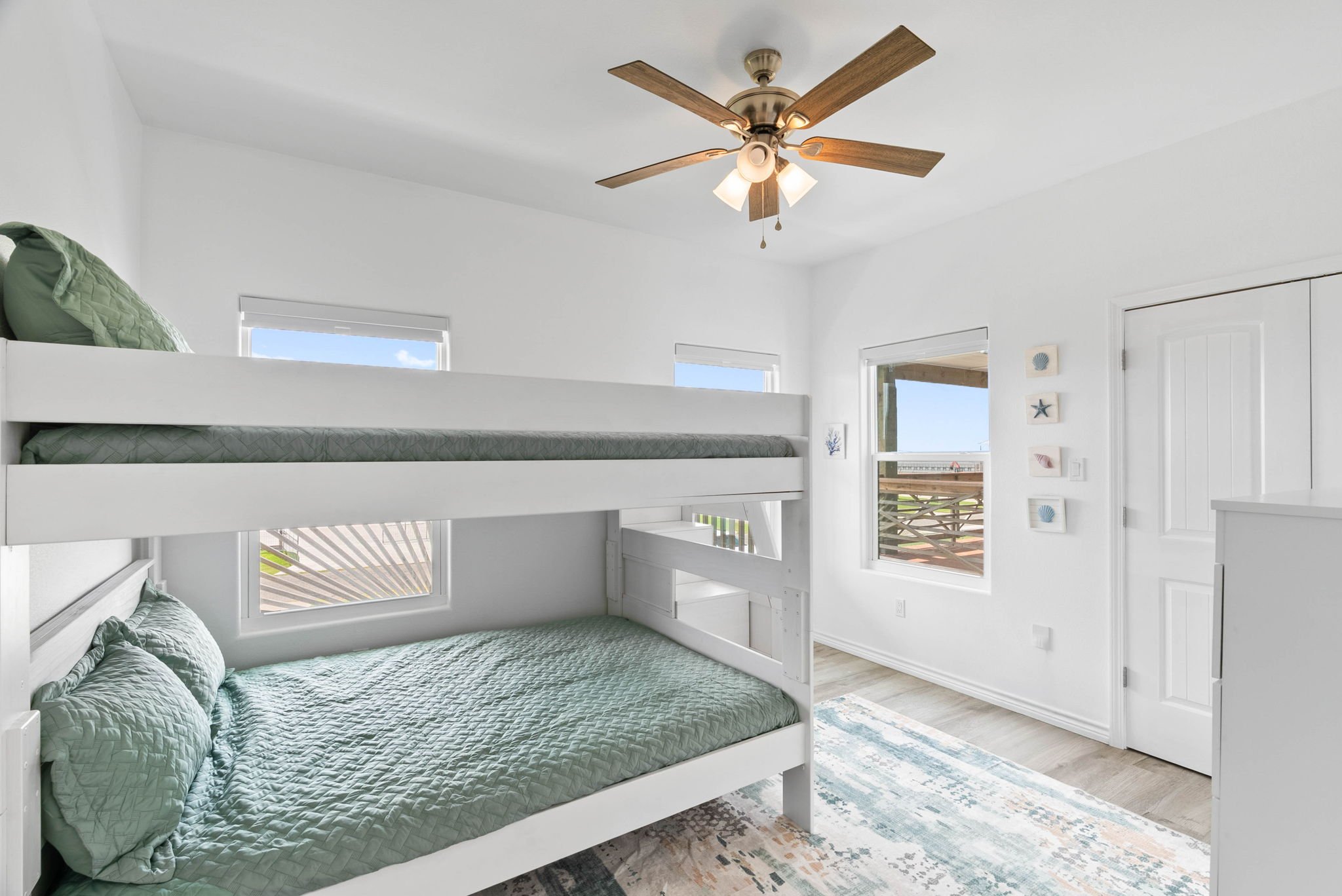 Family-friendly bunk room with white bunk beds, seafoam bedding and coastal accents