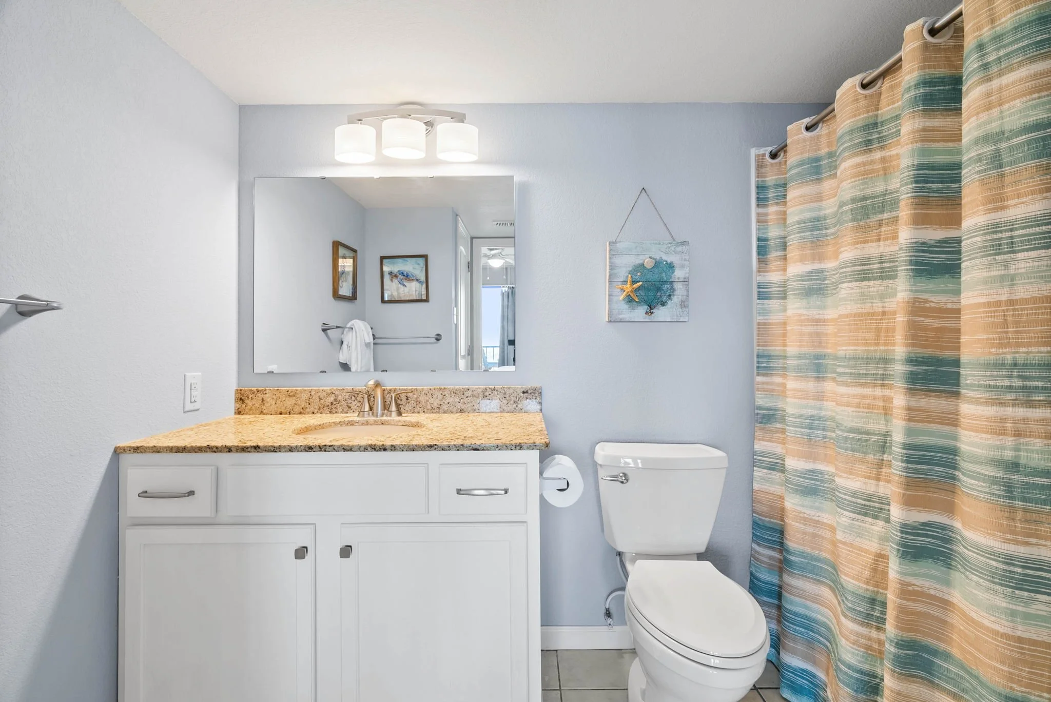 Bright beach-themed bathroom with granite counter and shower at Dayspring 402 Laguna Reef Rockport TX