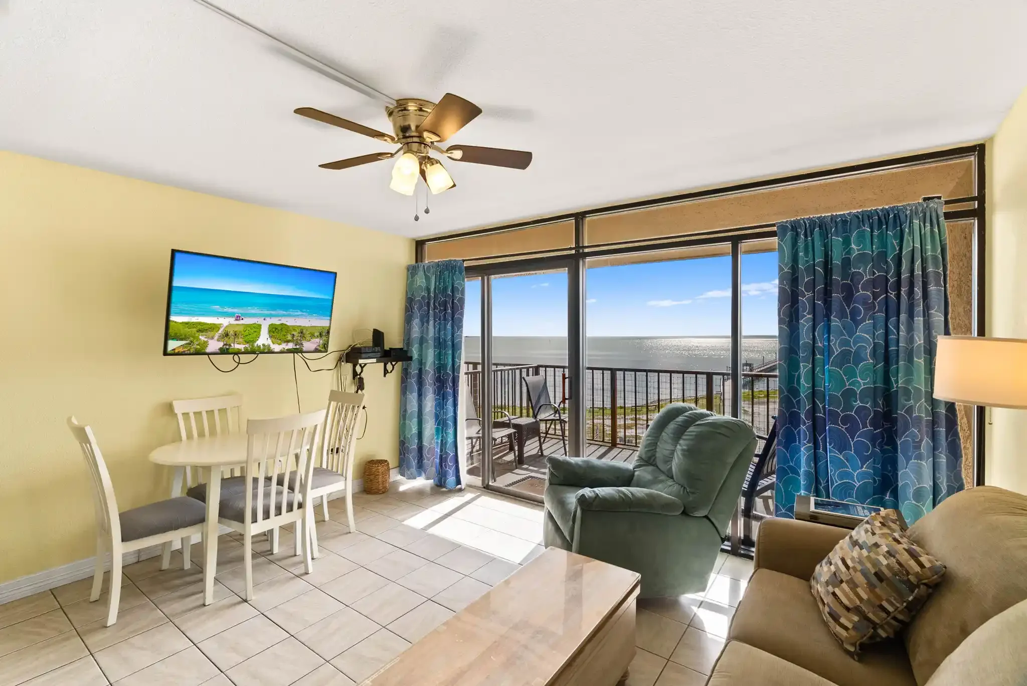 Sunlit living and dining area opening to a private balcony with expansive water views at this Rockport, TX coastal rental.