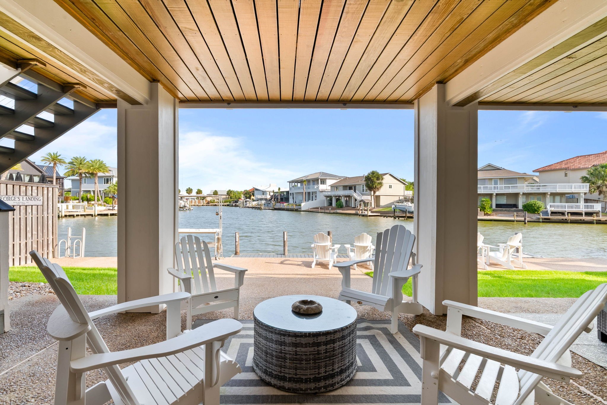 Covered waterfront patio with Adirondack chairs and private dock at a luxury Rockport TX vacation rental. 