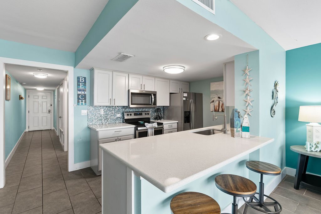 Breakfast bar seating and beach-themed decor in open kitchen at Beauty Blues condo in Laguna Reef Rockport.