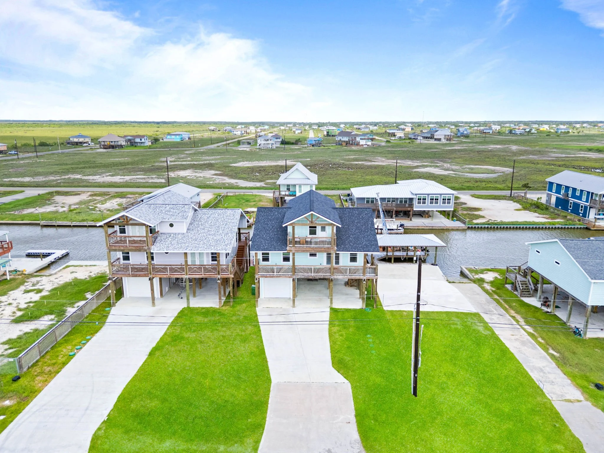 Aerial front view of a raised canal-front coastal home with balconies in Rockport, TX