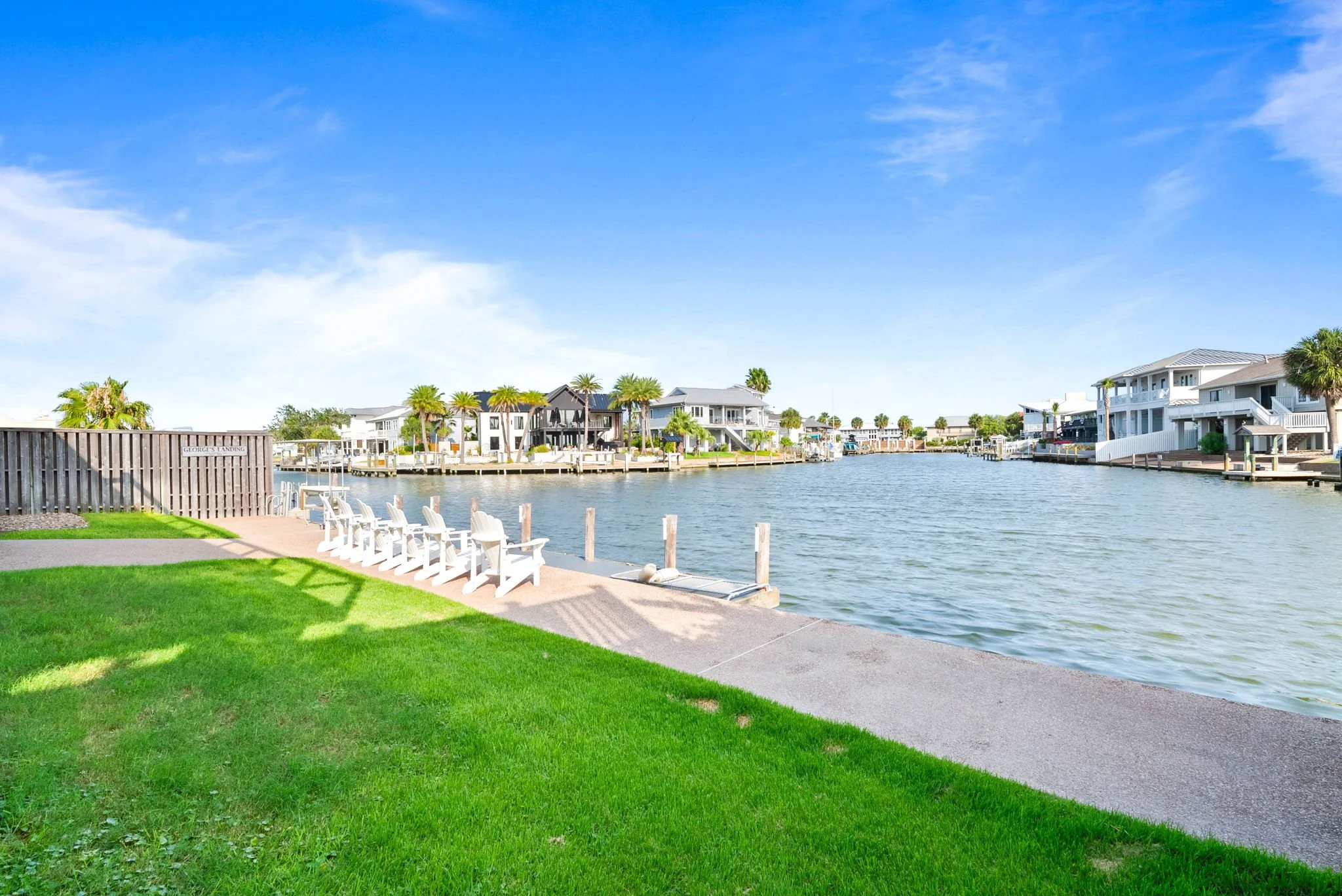 Spacious waterfront lawn with Adirondack seating and private dock at a luxury Rockport TX vacation rental.