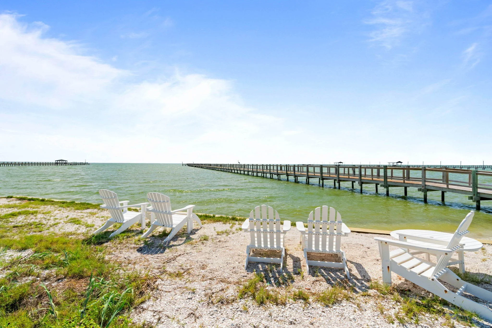 Waterfront lounge chairs on private shoreline overlooking fishing pier near Marina Del Rey Rockport TX vacation rental