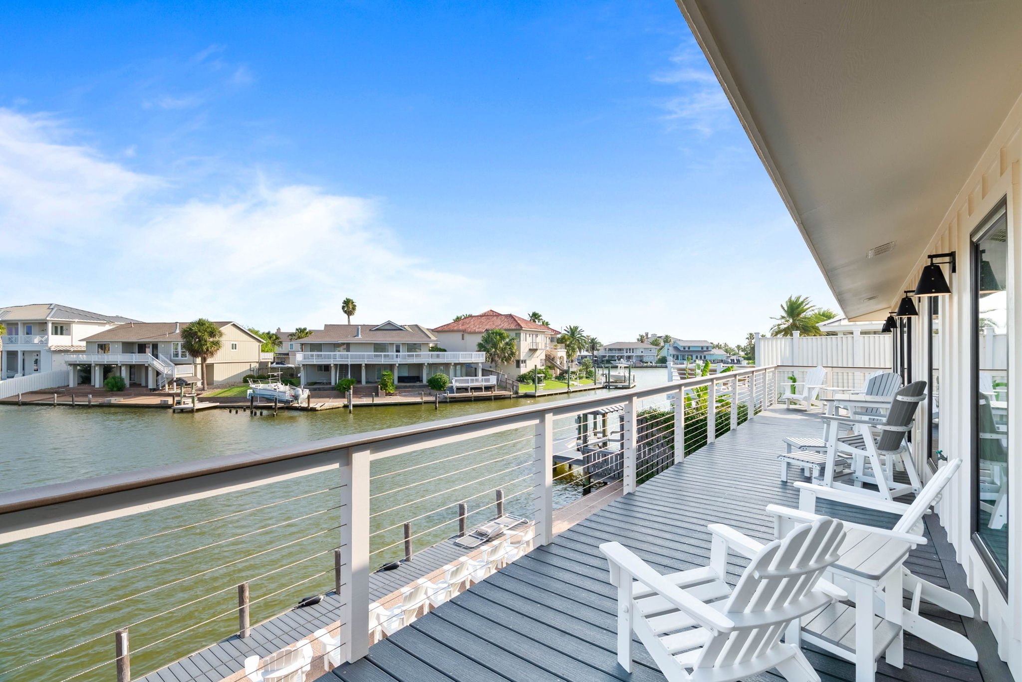 Covered waterfront patio with Adirondack chairs and private dock at a luxury Rockport TX vacation rental.