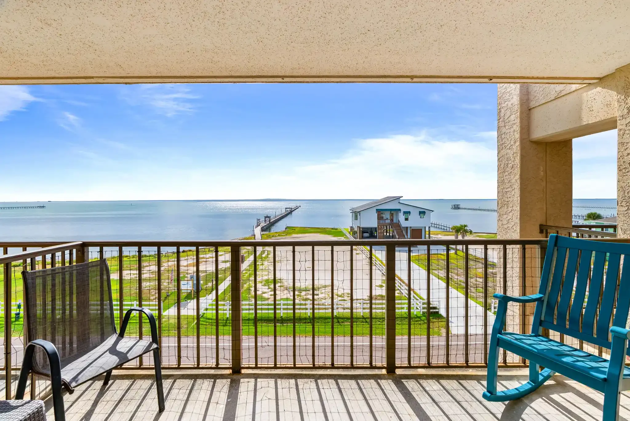 Private balcony with outdoor seating, sweeping bay views and a nearby fishing pier at this waterfront Rockport TX rental.