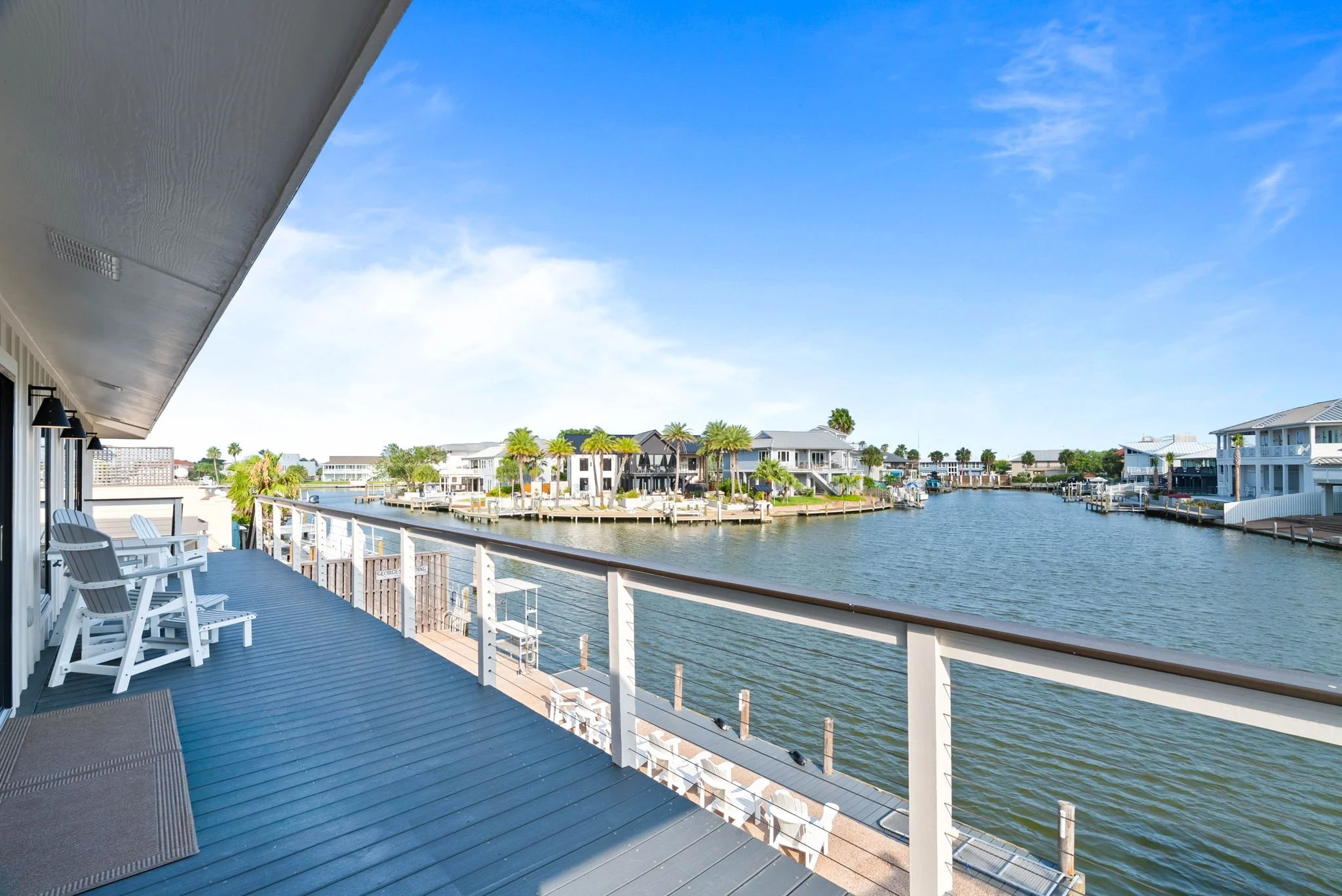 Waterfront balcony with Adirondack seating overlooking the canal at a luxury Rockport TX vacation rental.