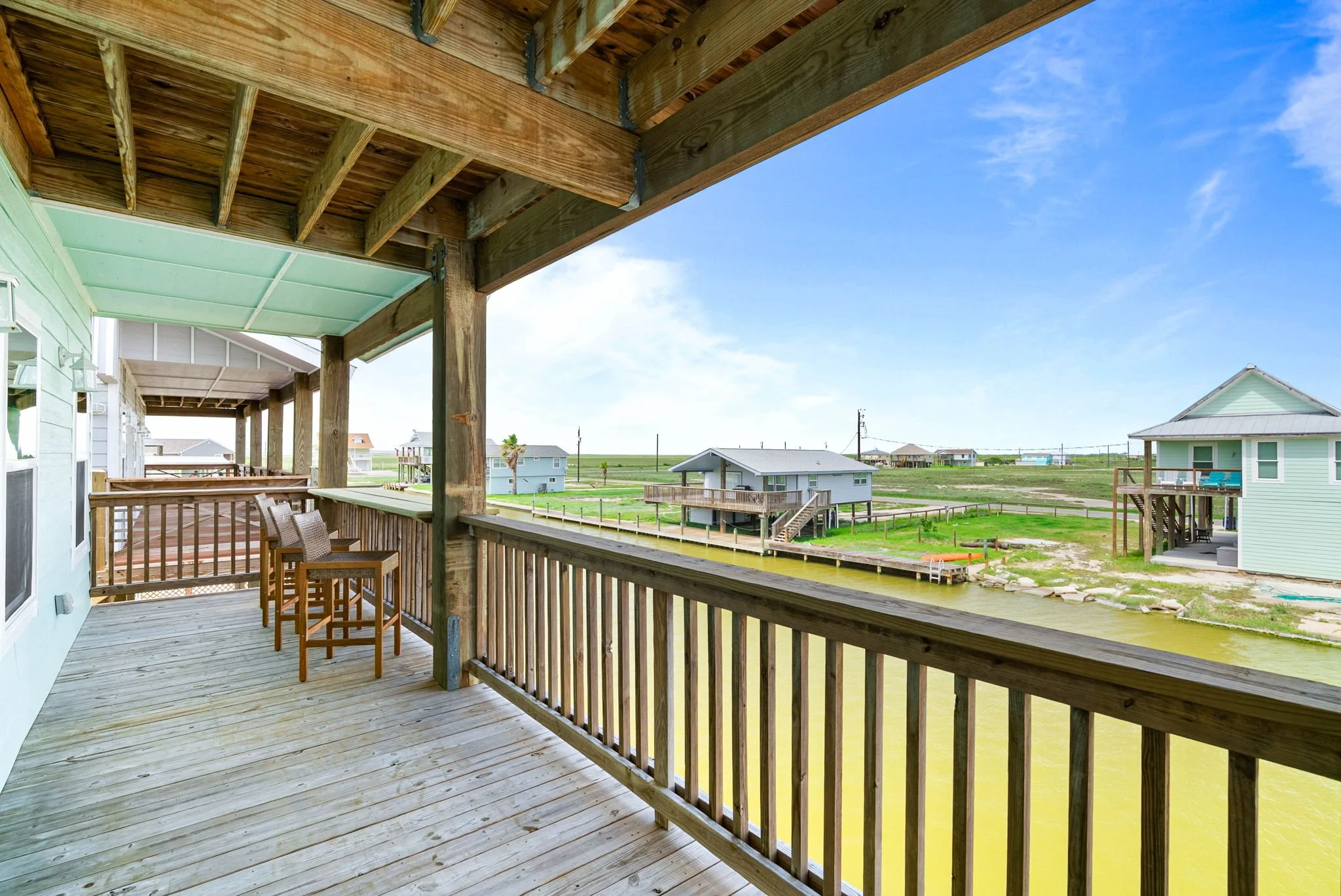 Covered canal-facing balcony with high-top seating at a waterfront Rockport rental