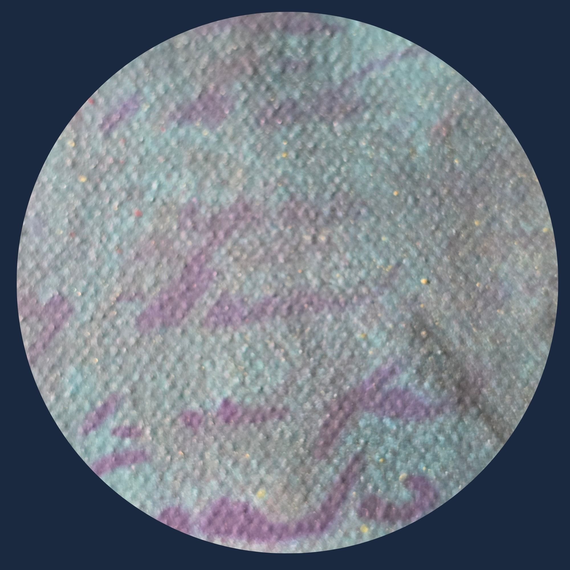 Close-up of a glittery, iridescent surface with pastel shades of purple, blue, and green, and tiny reflective specks.