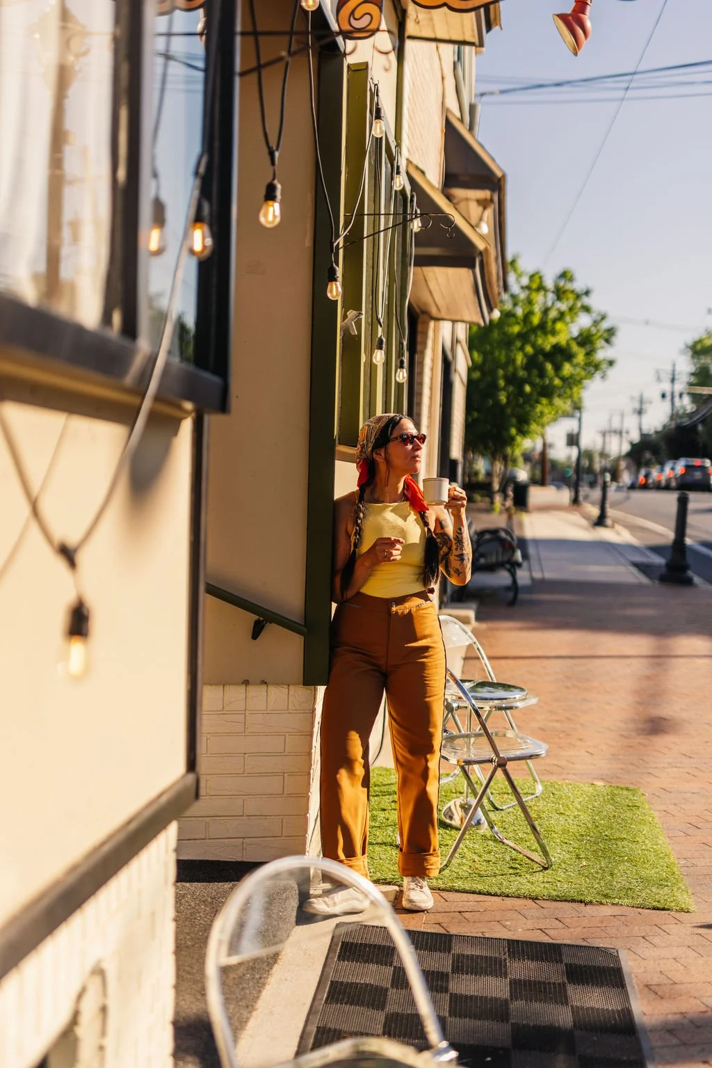 Little Coco Owner valentina fortuna out front with cup of coffee in the sun.