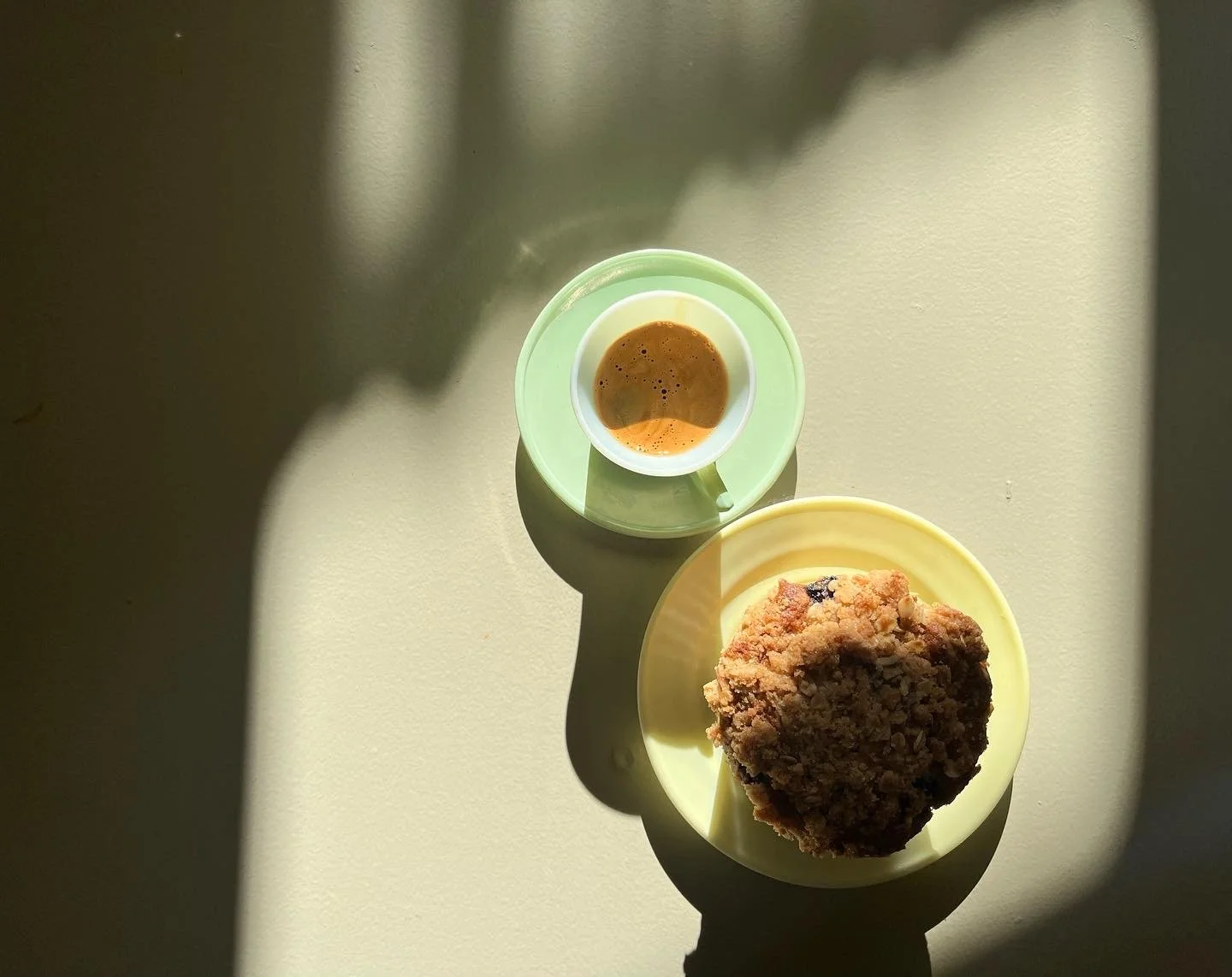 image of espresso shot in green cup next to muffin on yellow pastel plate
