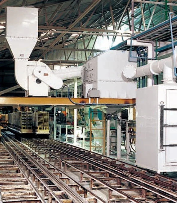 Industrial indoor setting with metal tracks, large machinery, and metal structures overhead.