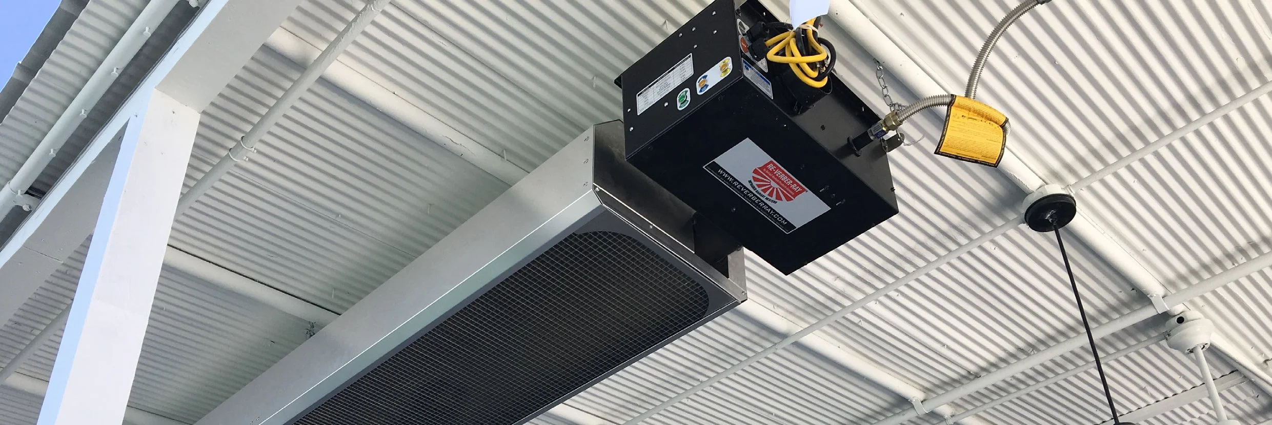 Ceiling-mounted industrial fire alarm and sensor system with black box and yellow wiring in a building ceiling.