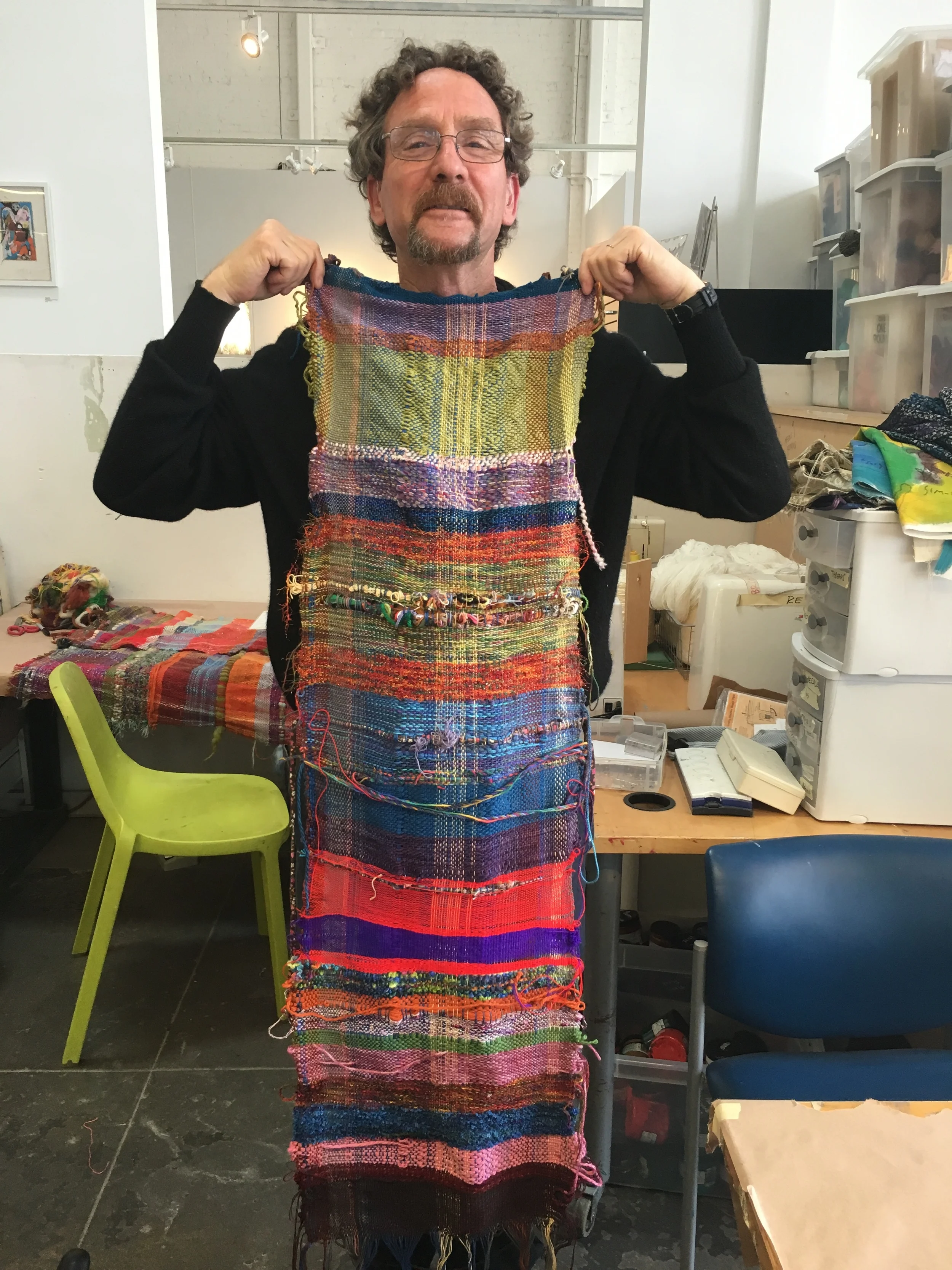 Artist Pete Salsman holding up the part of the communally woven piece pre garment making.