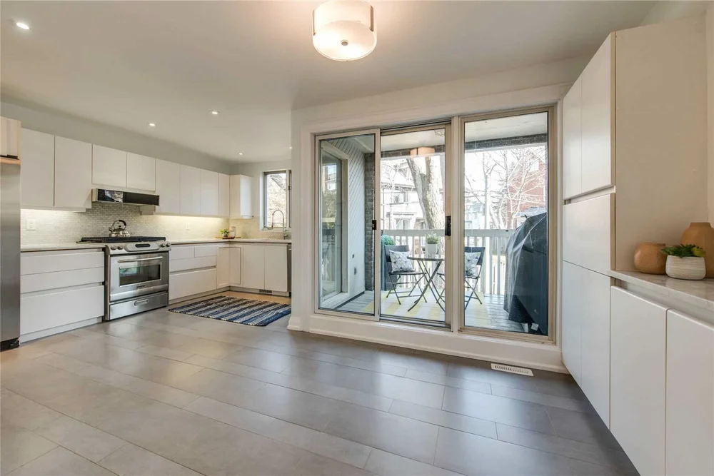 North Central Toronto kitchen renovation by First Place Homes: white cabinets and a sliding door to the deck