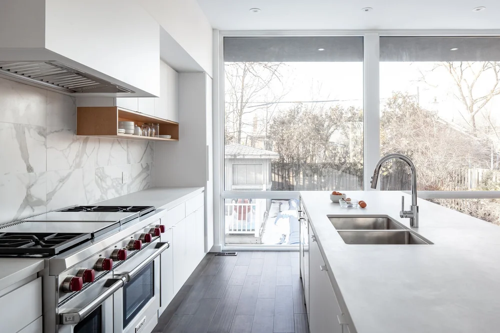 Etobicoke kitchen renovation by First Place Homes: white cabinets, marble backsplash and a pro range