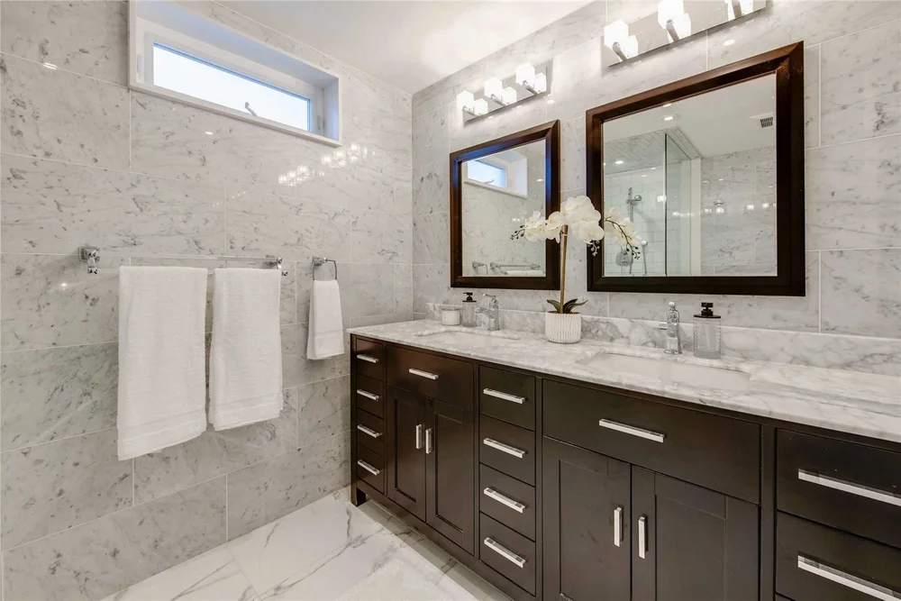 Bathroom renovation in North Central Toronto by First Place Homes: marble tile, dark double vanity and framed mirrors