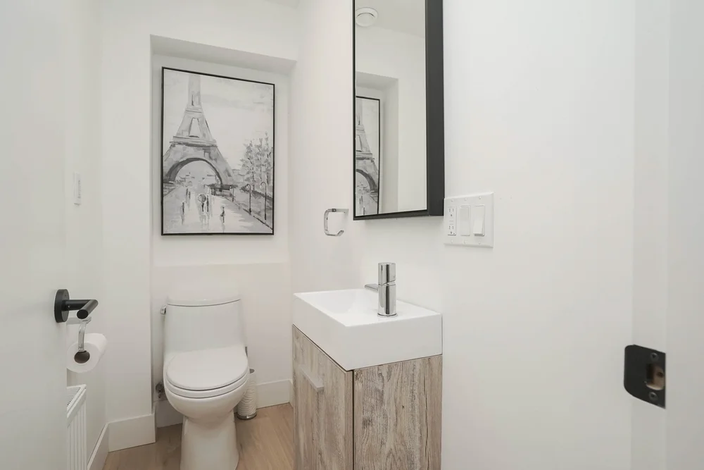 High Park powder room by First Place Homes: wall-hung sink and black fixtures