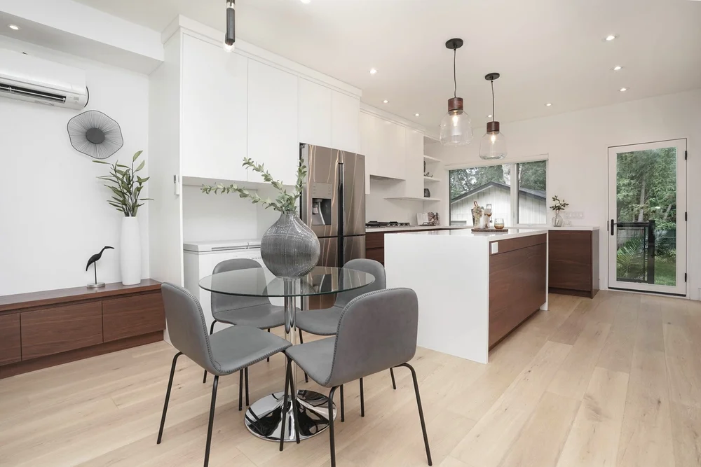 High Park home renovation by First Place Homes: white kitchen with a walnut island and a dining table by the window