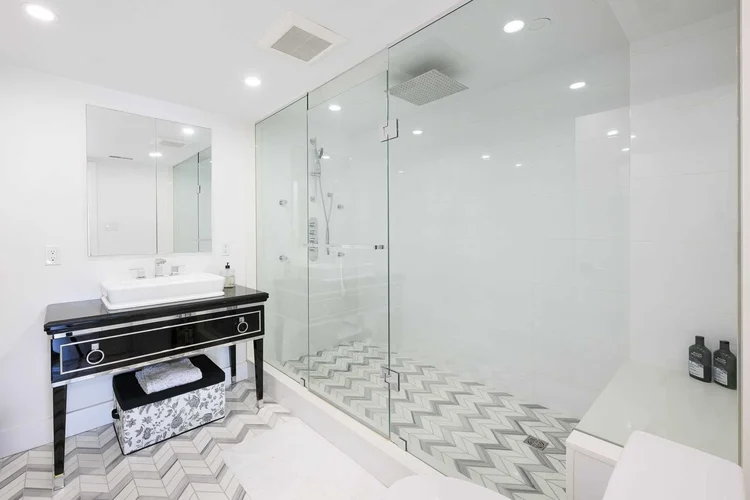 Toronto townhome bathroom renovation by First Place Homes: frameless glass shower and chevron tile floor
