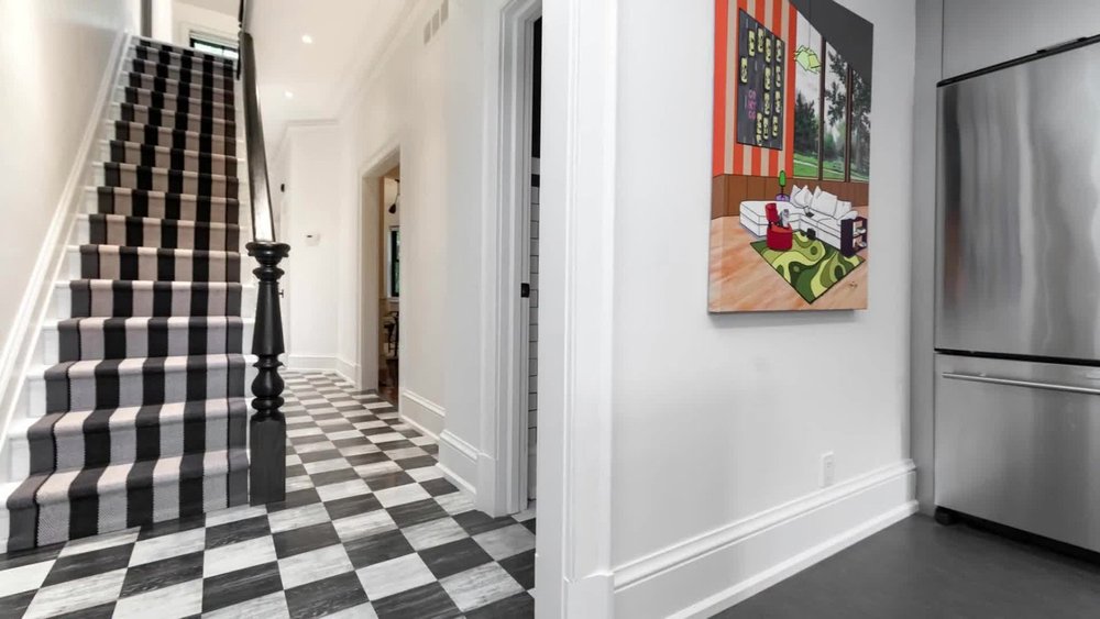 Victorian home renovation in Toronto by First Place Homes: front hall with a stair runner and a checkerboard tile floor