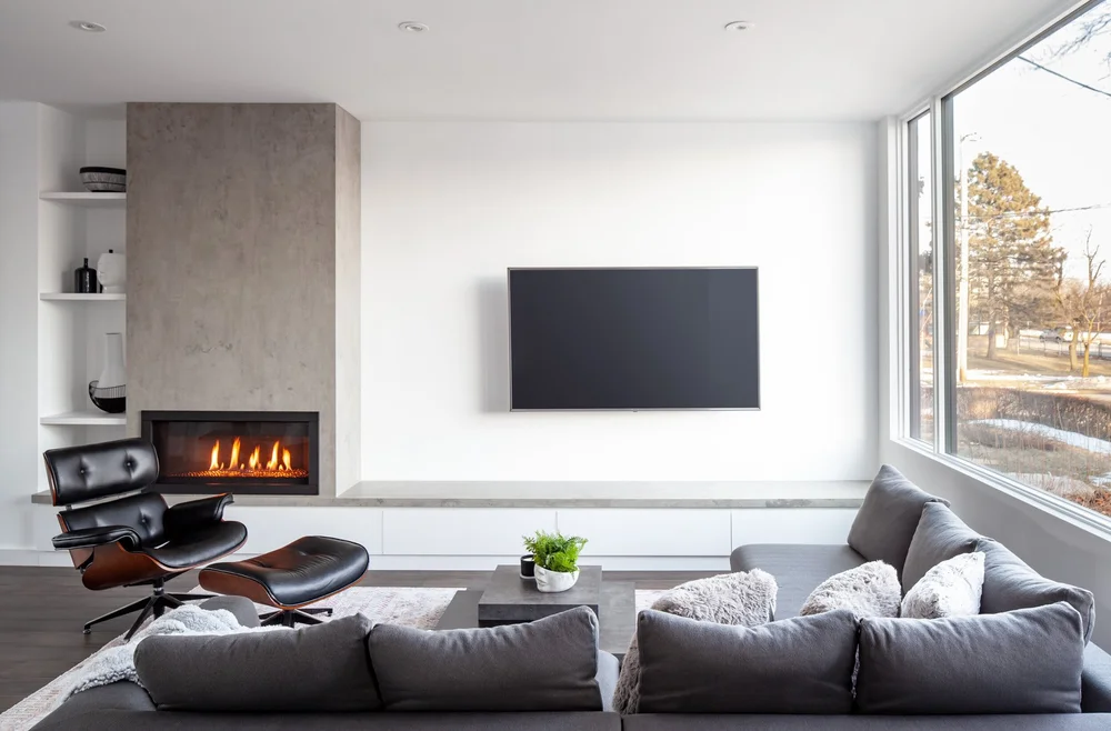 Etobicoke living room by First Place Homes: concrete fireplace wall, lounge chair and a corner window