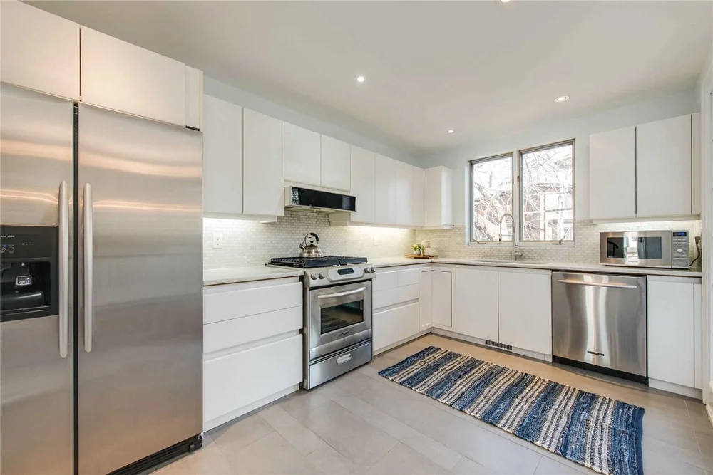 North Central Toronto kitchen renovation by First Place Homes: white cabinets, stainless appliances and a window over the sink