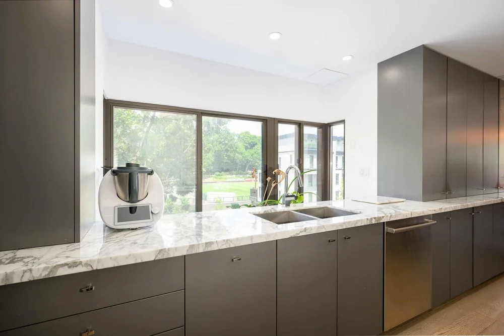 Toronto townhome kitchen renovation by First Place Homes: grey cabinets, marble counter and a garden window