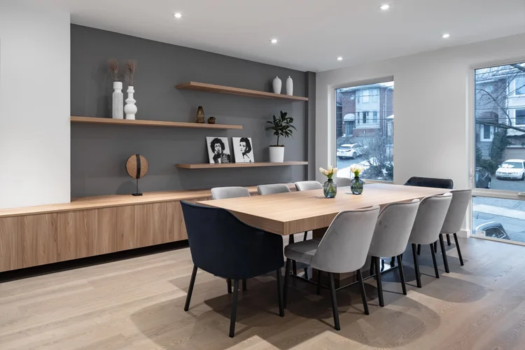 West side Toronto dining room by First Place Homes: long wood table, floating shelves and a window wall