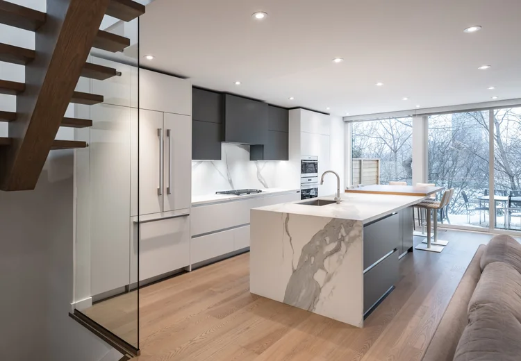 West side Toronto kitchen renovation by First Place Homes: marble waterfall island under a new stair