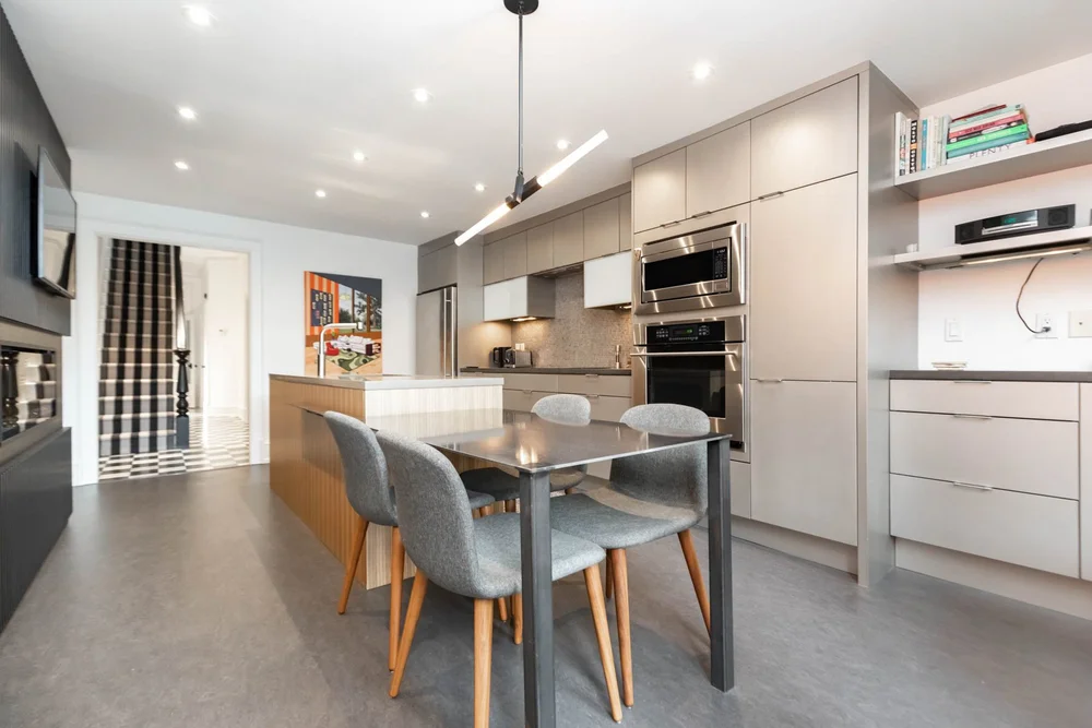 Victorian home renovation in Toronto by First Place Homes: kitchen with grey cabinets, dining table and the stair hall beyond