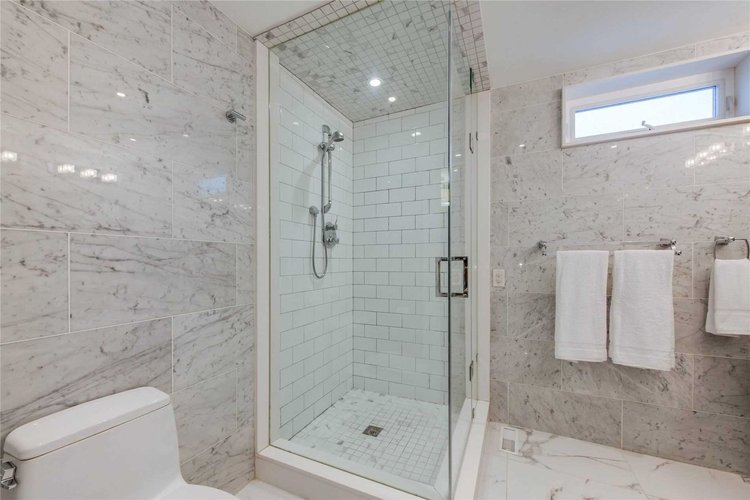 Walk-in glass shower with marble tile in a North Central Toronto bathroom renovation by First Place Homes