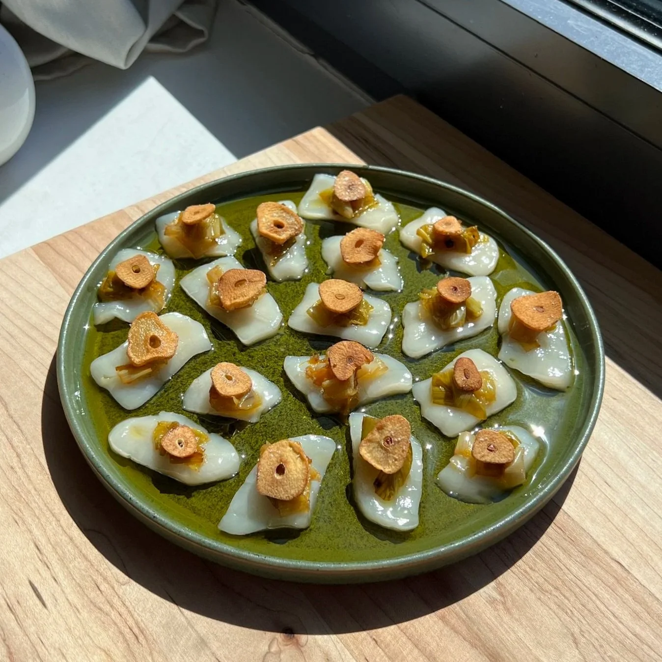 Scallop Crudo with Confit Leeks, Pink Peppercorns, and Crispy Garlic