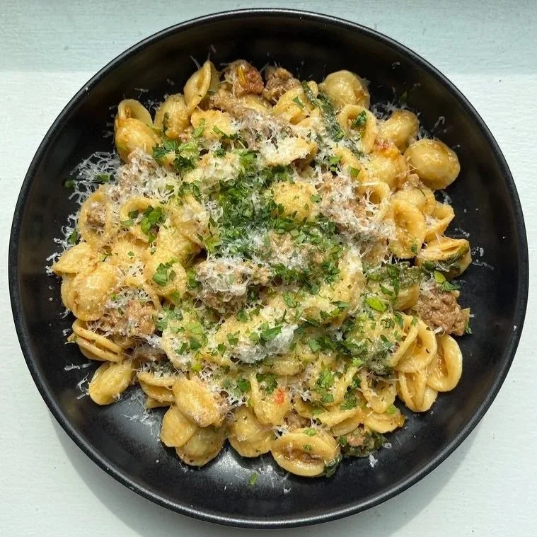 Bowl of lamb and swiss chard pasta, topped with parsley and parmesan