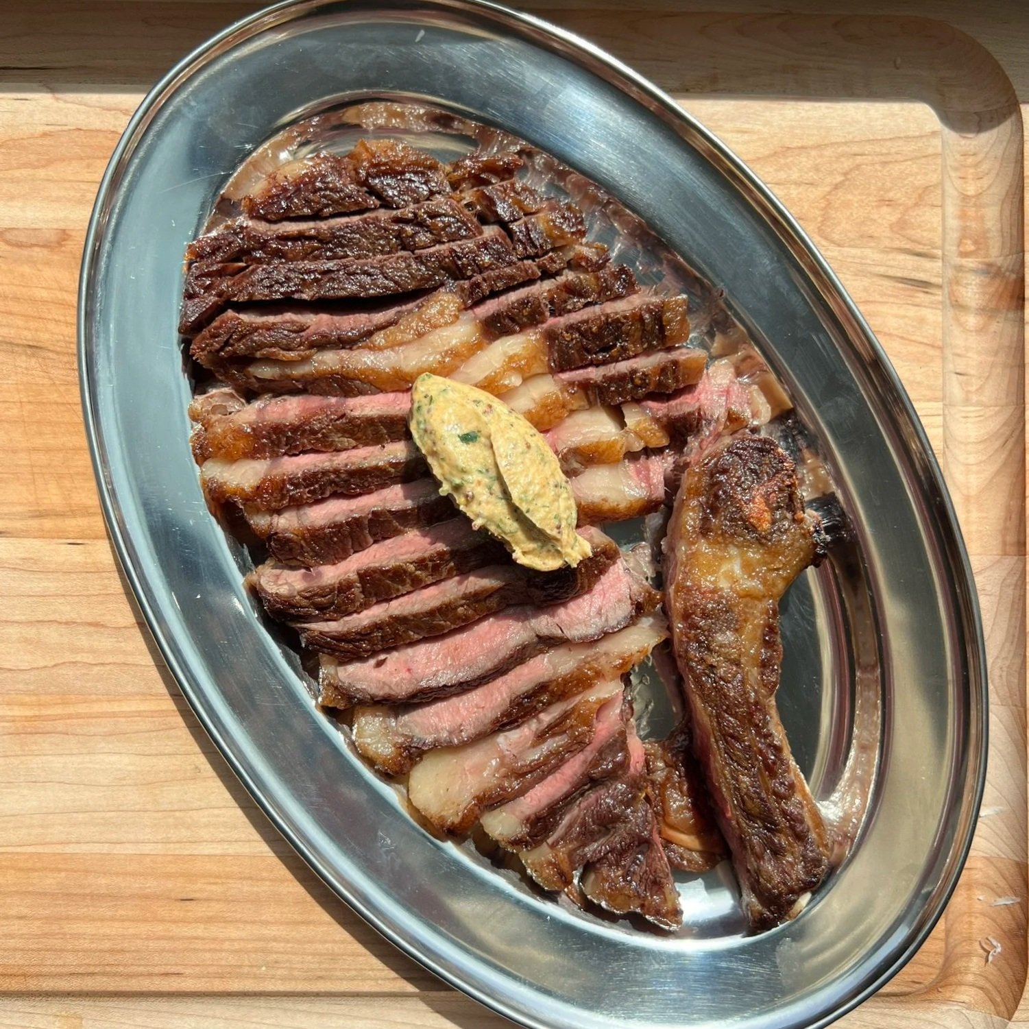Sliced steak with a mound of double mustard butter on top