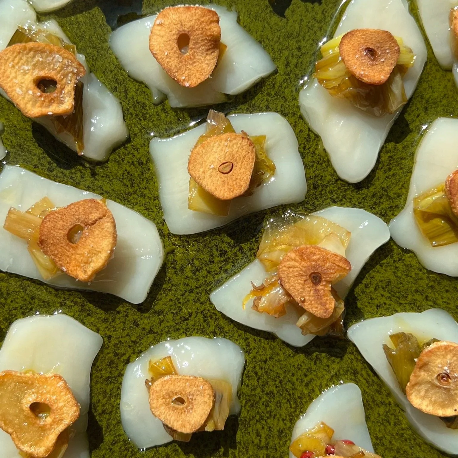 Scallop crudo topped with confit leeks and crispy garlic