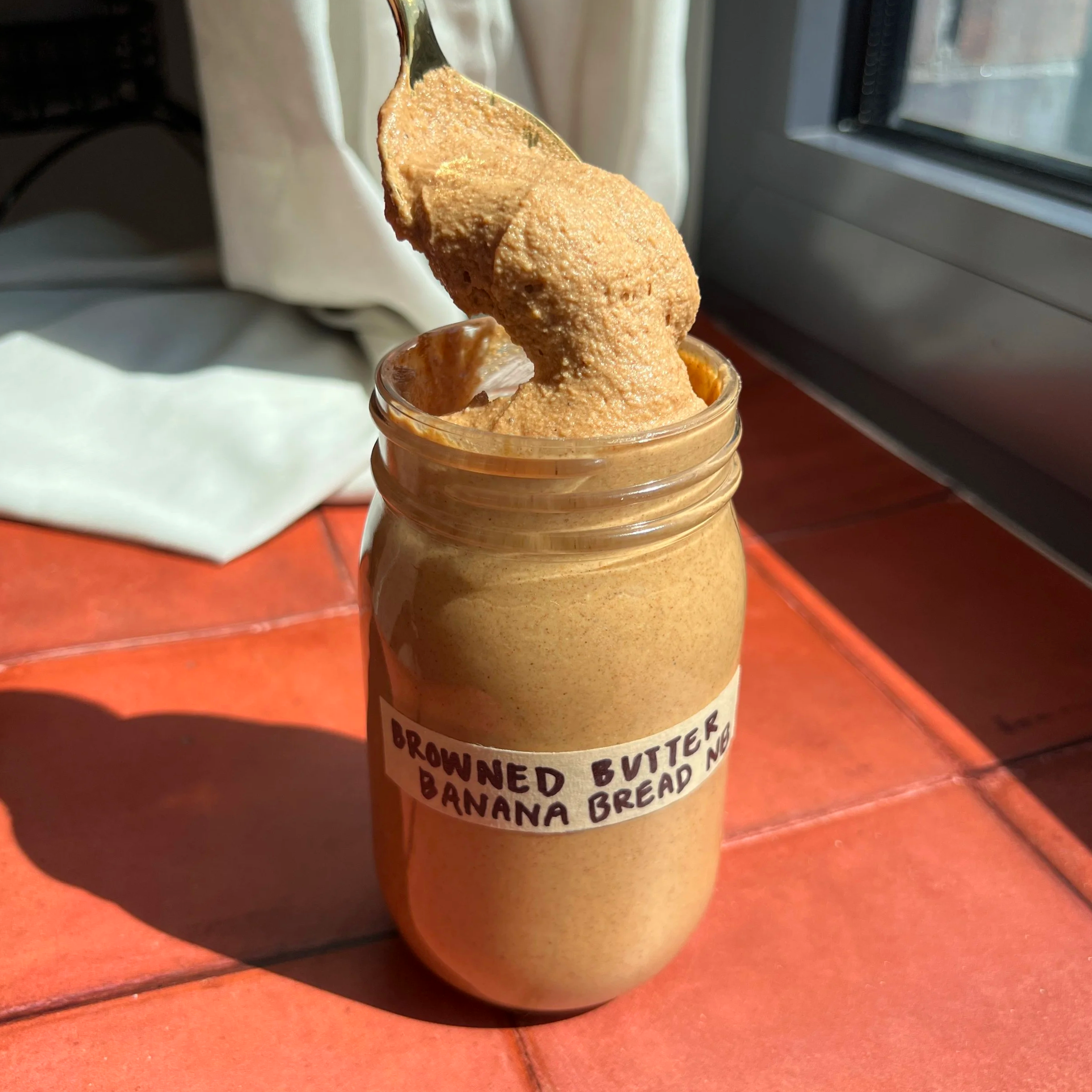 Spoon scooping out browned butter banana bread nut butter from a jar