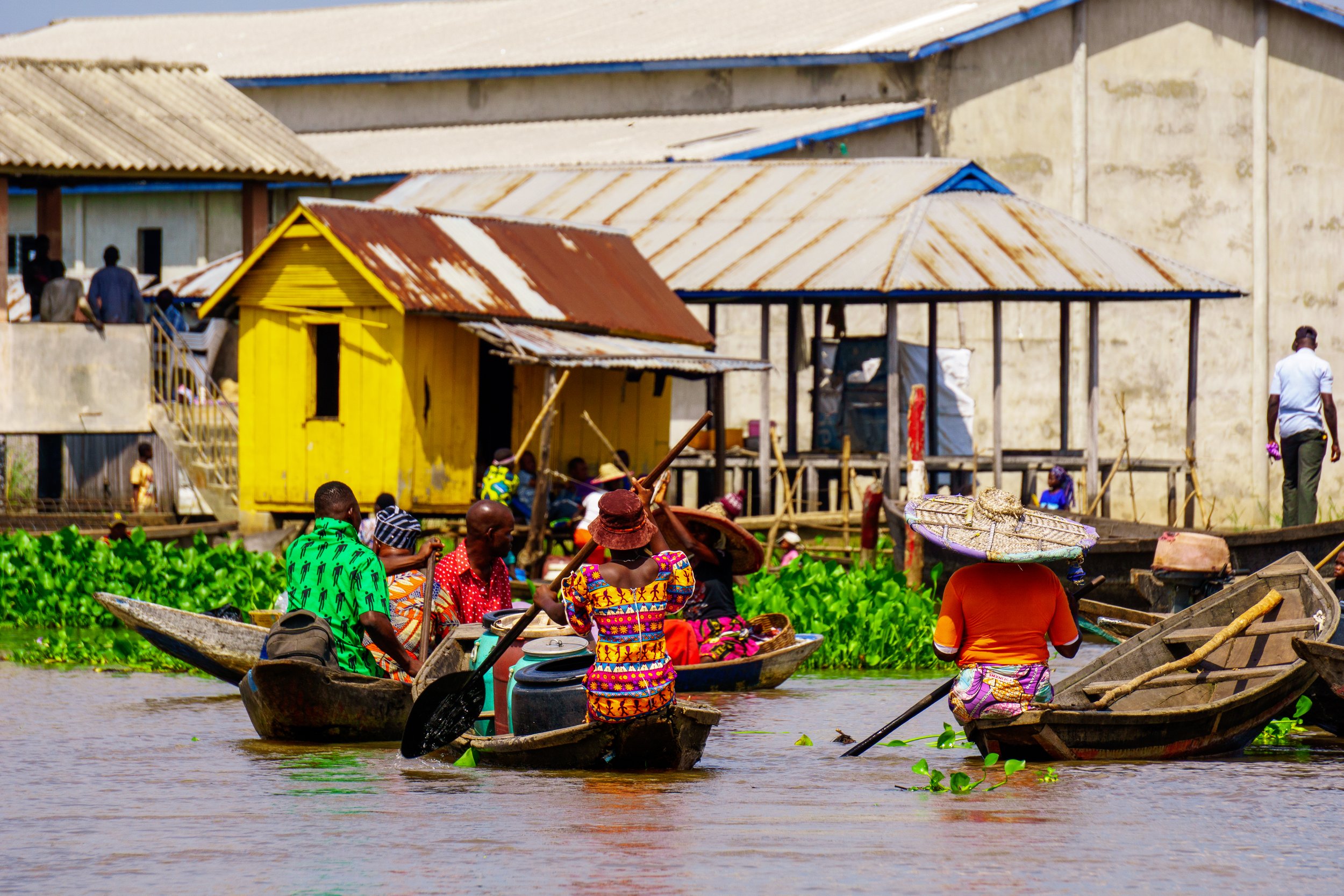 Townspeople in colorful clothing commuting by canoe in Ganvie, Benin in West Africa. The floating village is sometimes called "the Venice of Africa.” (Copy)