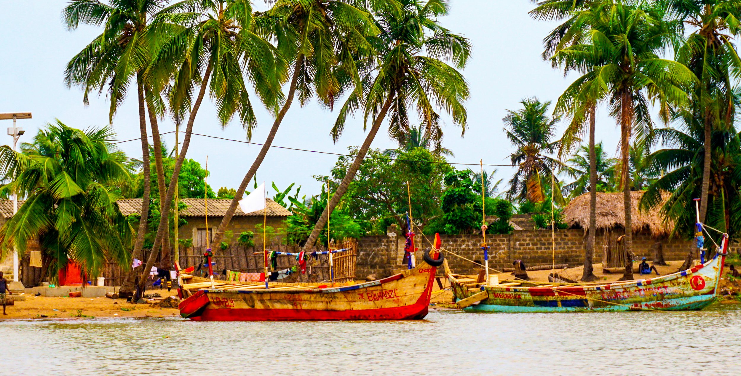 Colorful boats docked on the palm-tree-lined banks of the Mono River near Grand Popo, Benin in West Africa. (Copy)