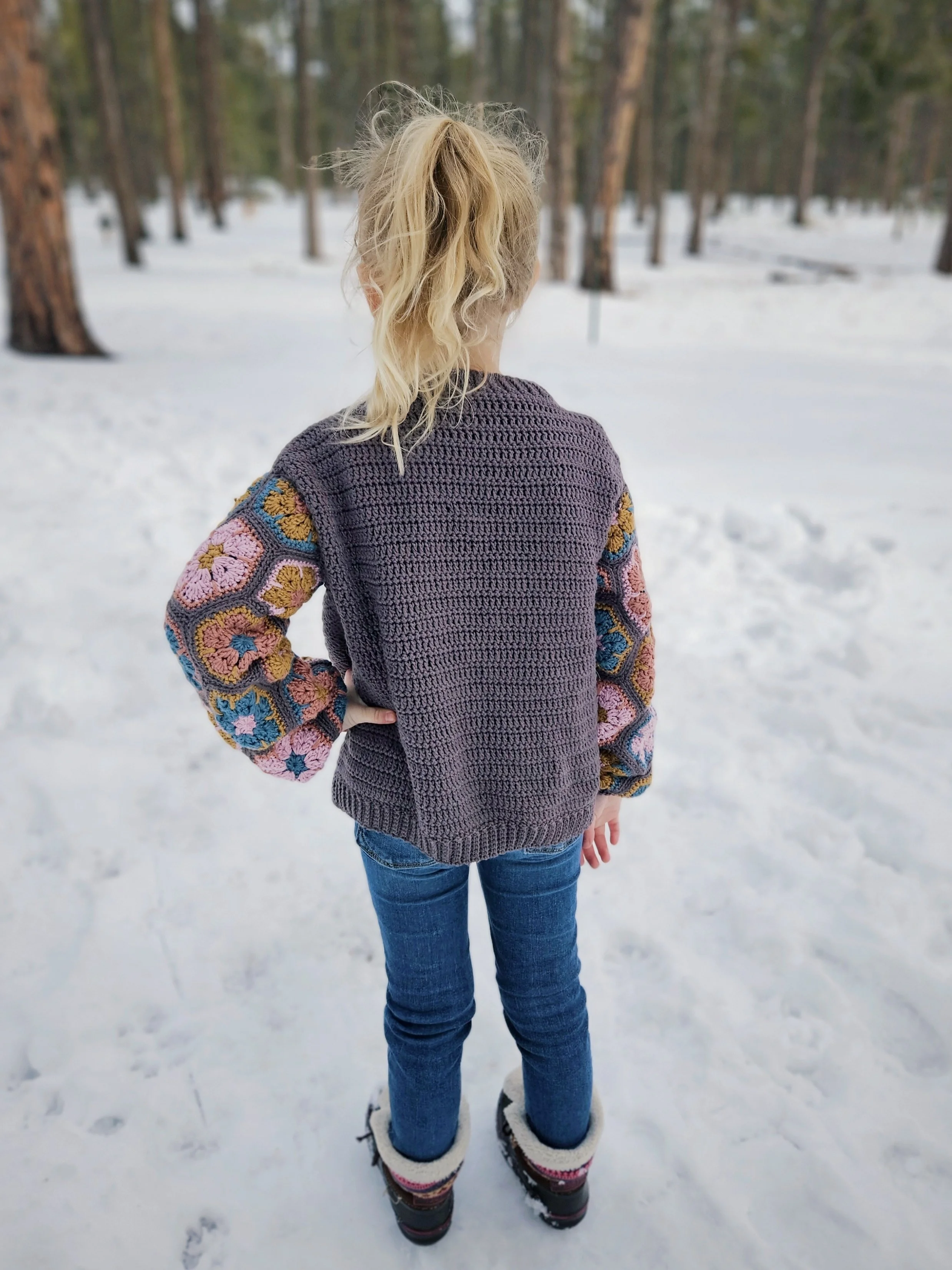 Beginner-friendly crochet cardigan pattern in child and adult sizes, featuring floral motif sleeves.