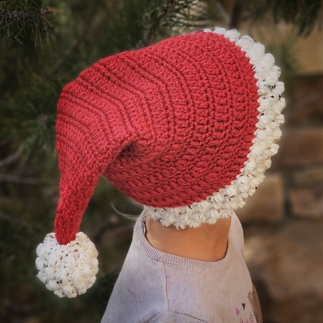 Santa hat crochet patten being modeled with bobble stitch details and a pompom